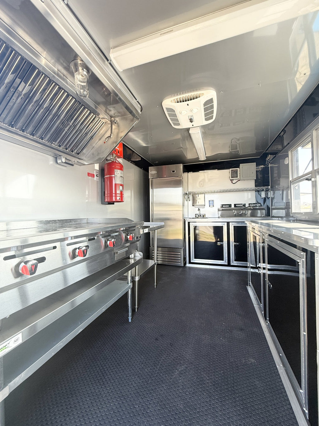 Interior of a food truck with stainless steel appliances and equipment.