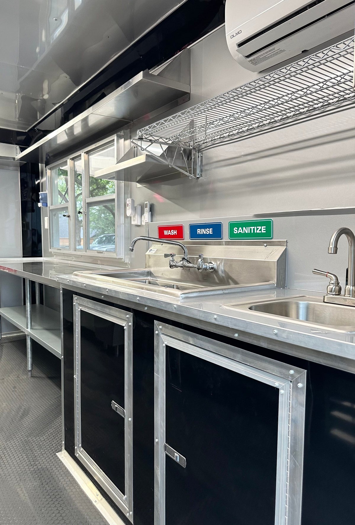 Three-compartment sink with wash, rinse and sanitize signage and hand sink in the 14 FT Burger Trailer