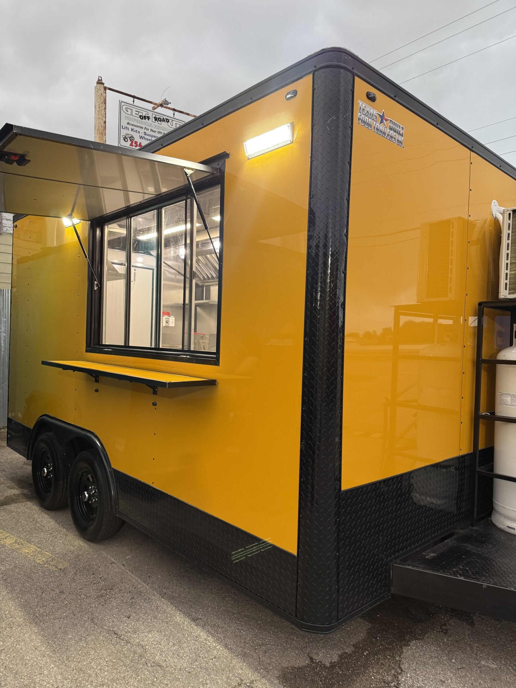 14 FT yellow cooking trailer, exterior three-quarter view with the concession window open