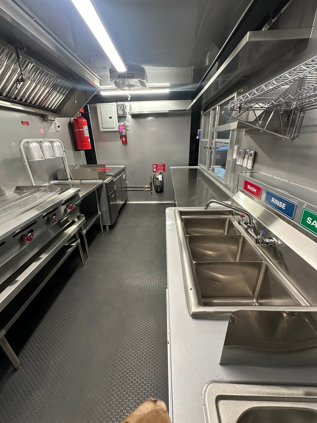 Stainless prep tables and wire wall shelving along the window side of the 14 FT Burger Trailer