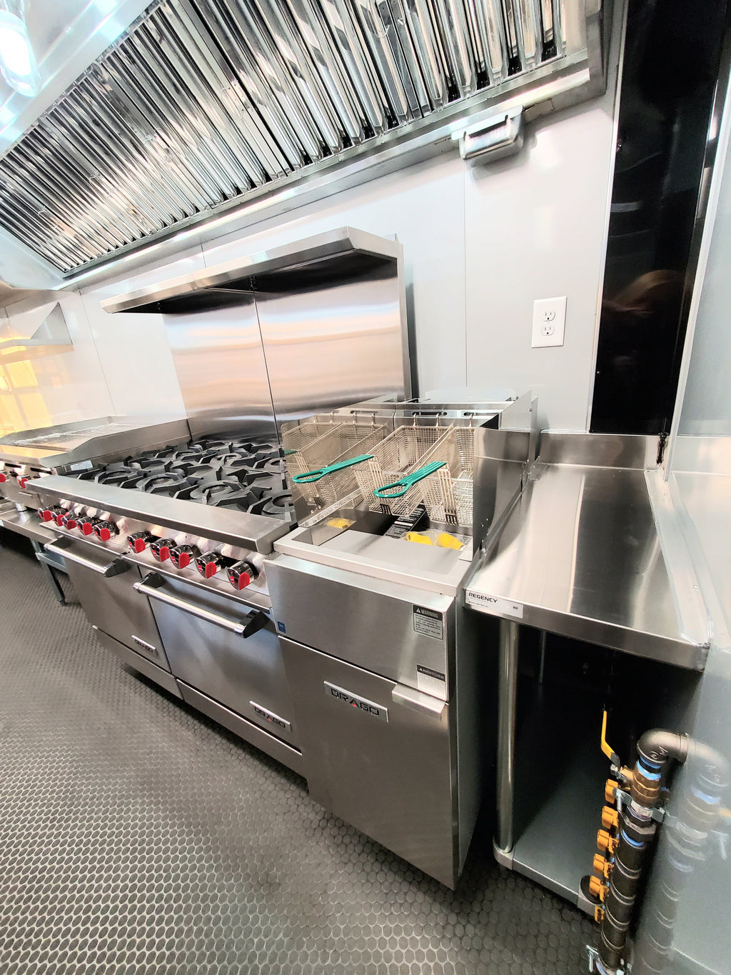 Stainless steel commercial kitchen with large stove and exhaust hood