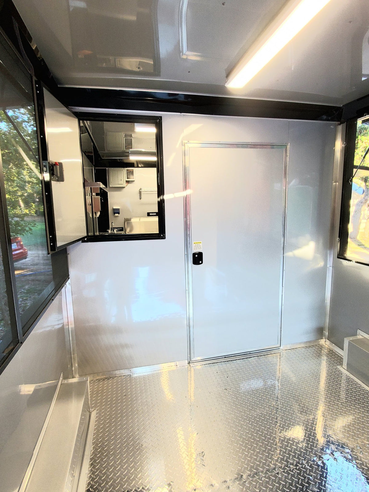 Modern kitchen trailer interior with glass door and metallic floor.