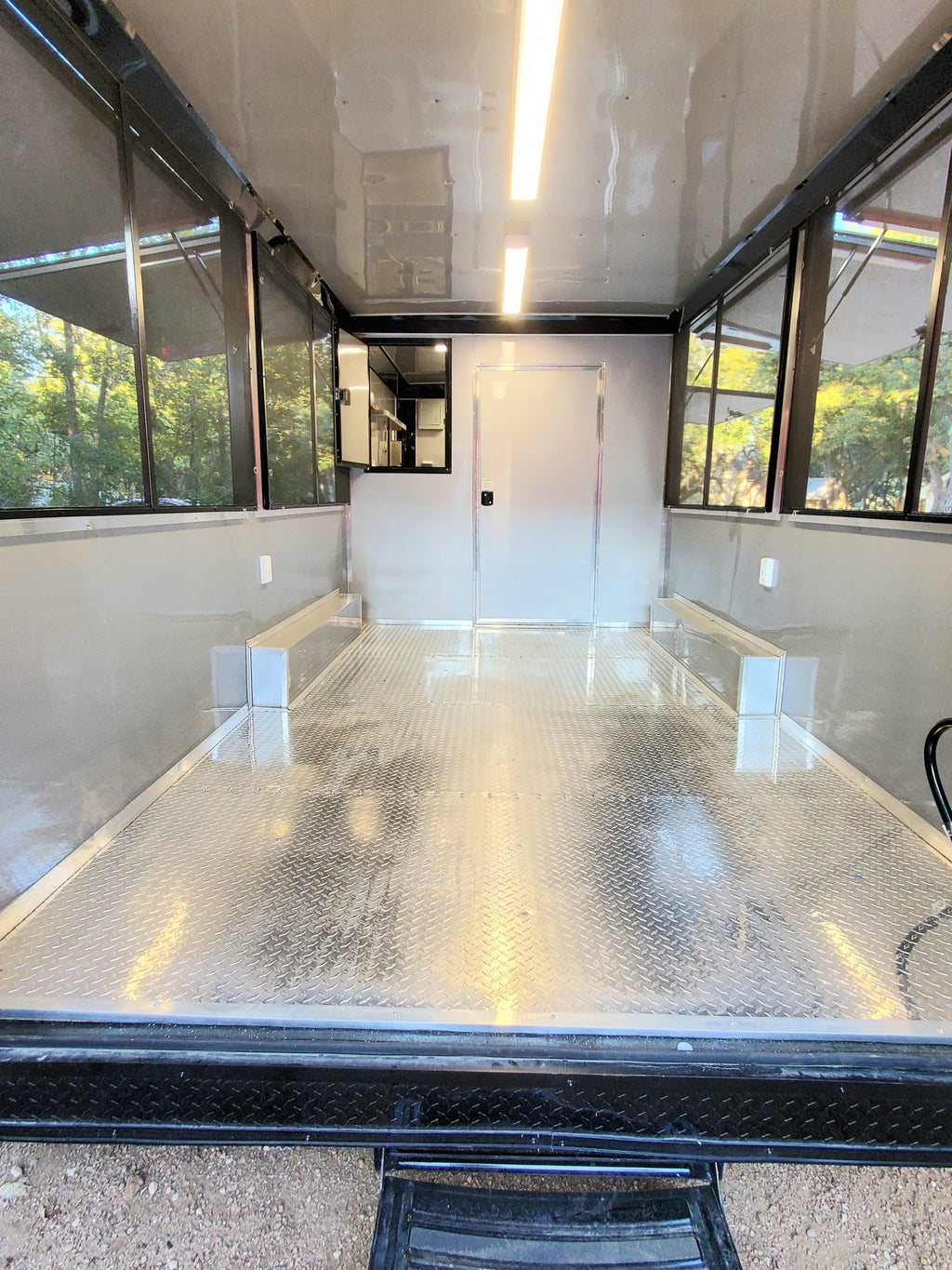Interior of a trailer with a metal floor and large windows.