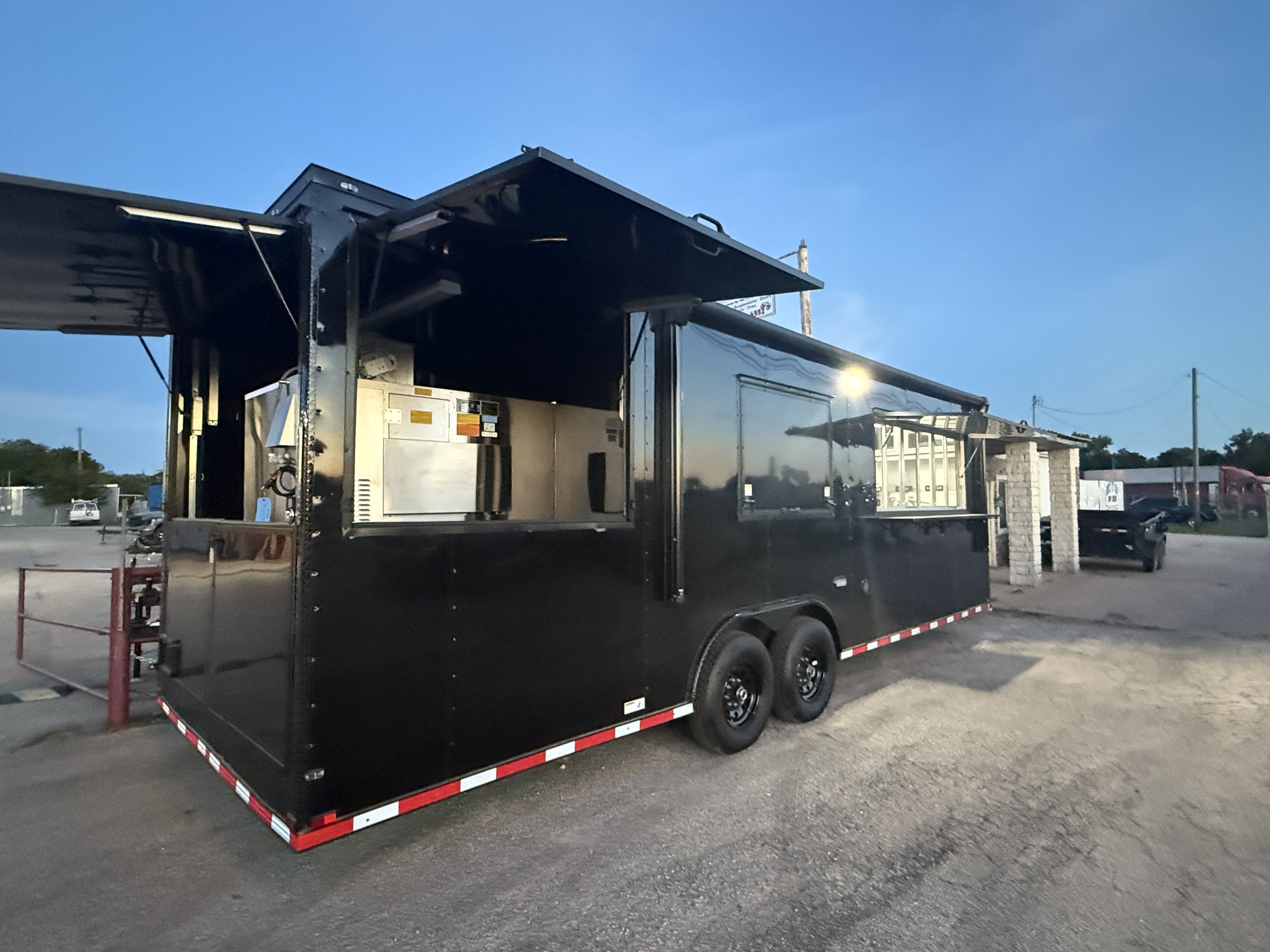 26 FT concession porch trailer, fully loaded, exterior three-quarter at dusk with awnings raised
