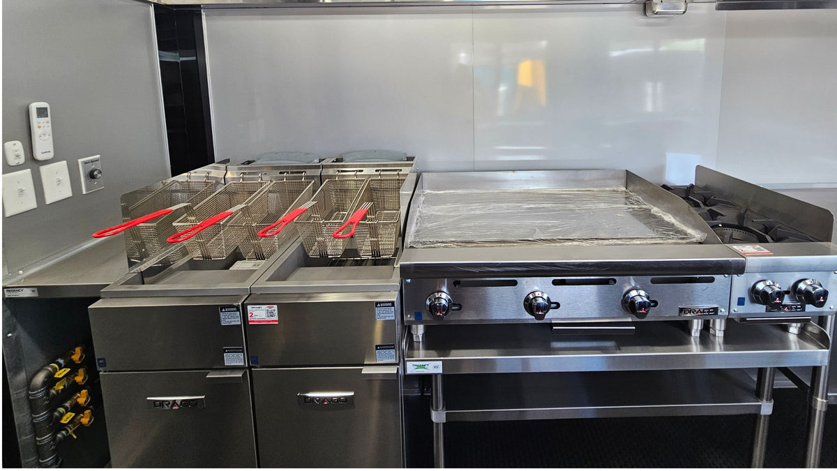 Commercial kitchen equipment installed in a Texas Built food trailer, with twin deep fryers, a flat-top griddle and a gas range