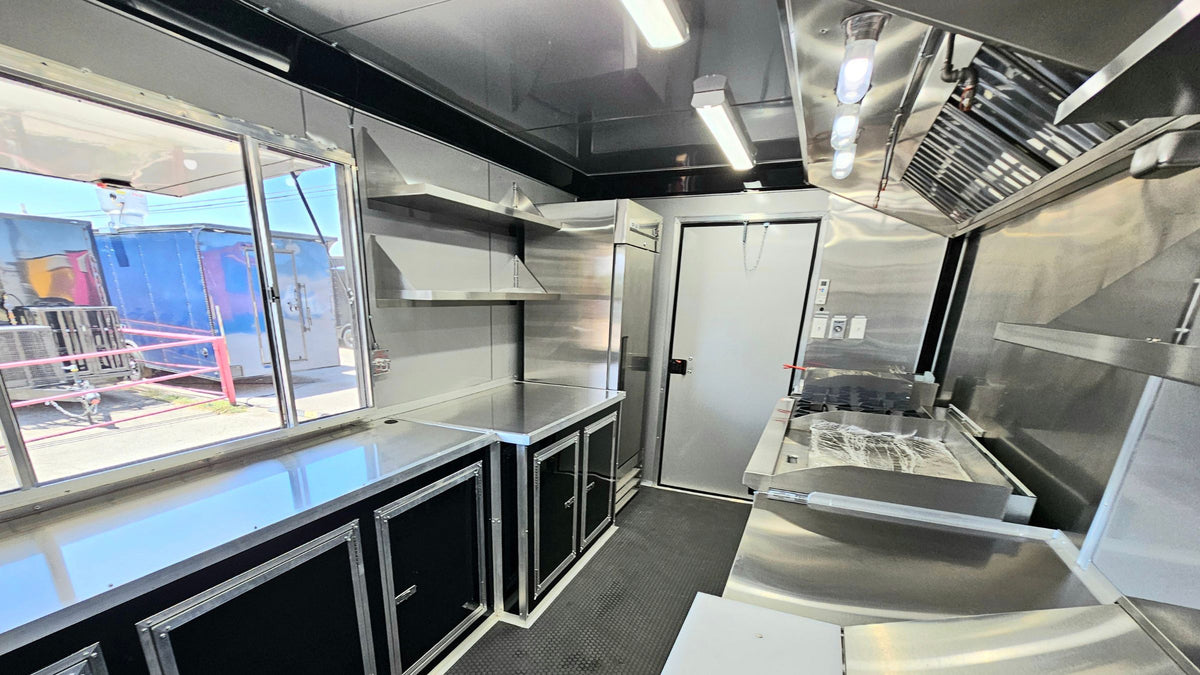 Inside a custom food truck kitchen built in Texas, with stainless counters, commercial refrigeration and a service window