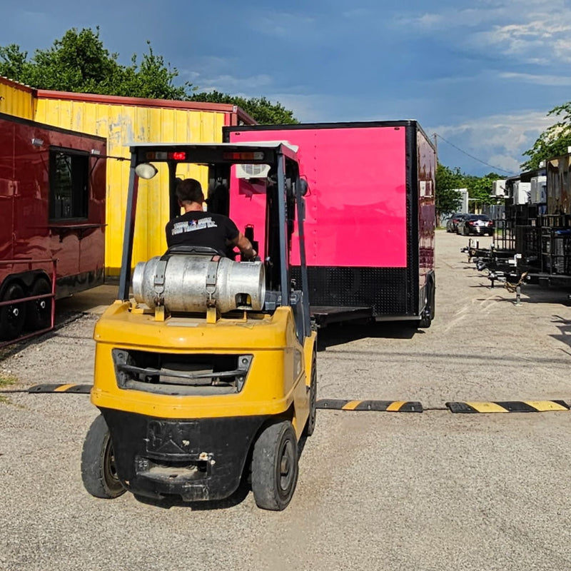 Forklift moving a finished food trailer through the Texas Built yard in Belton, Texas, with completed trailers lined up alongside