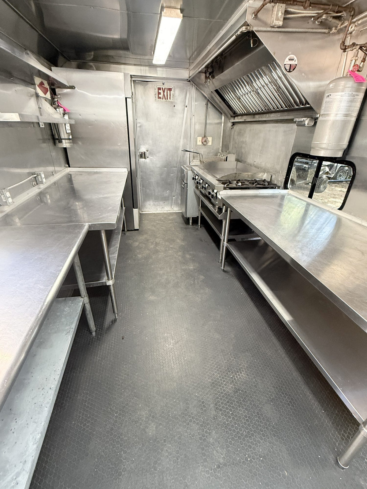 Interior looking toward the rear door, stainless prep counters down both sides and a fire extinguisher by the exit