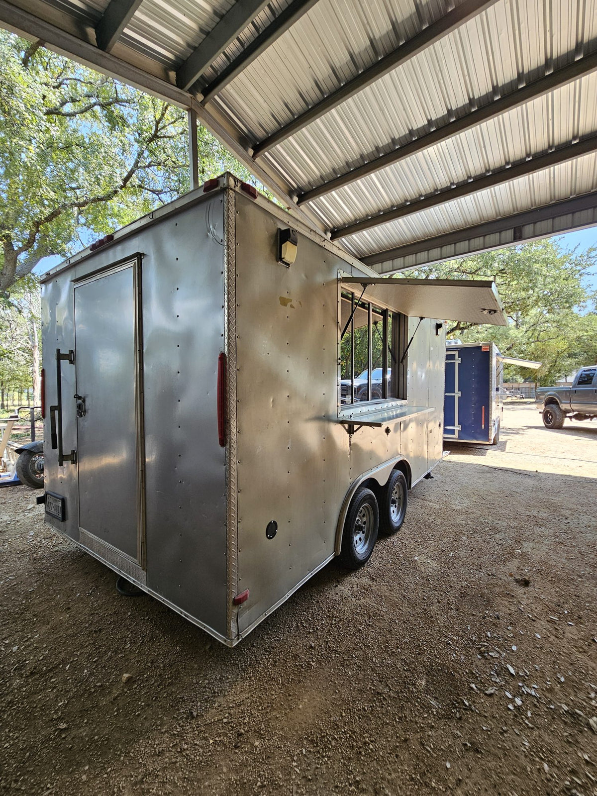 Silver concession trailer outside with the serving window awning open
