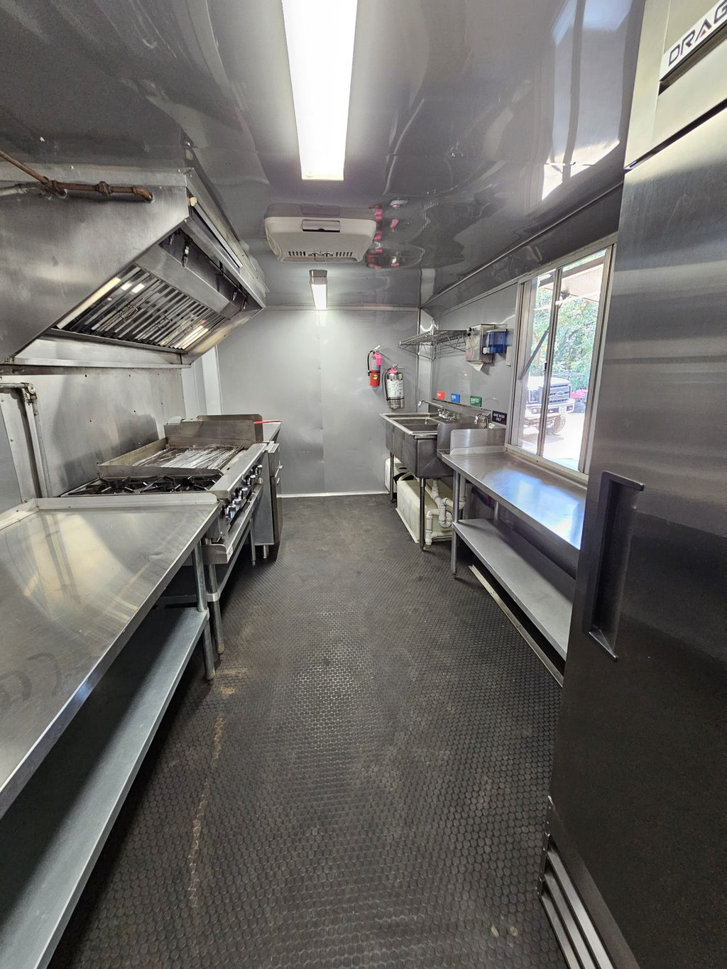 Interior looking down the trailer, stainless prep counters both sides and the cook line under the vent hood