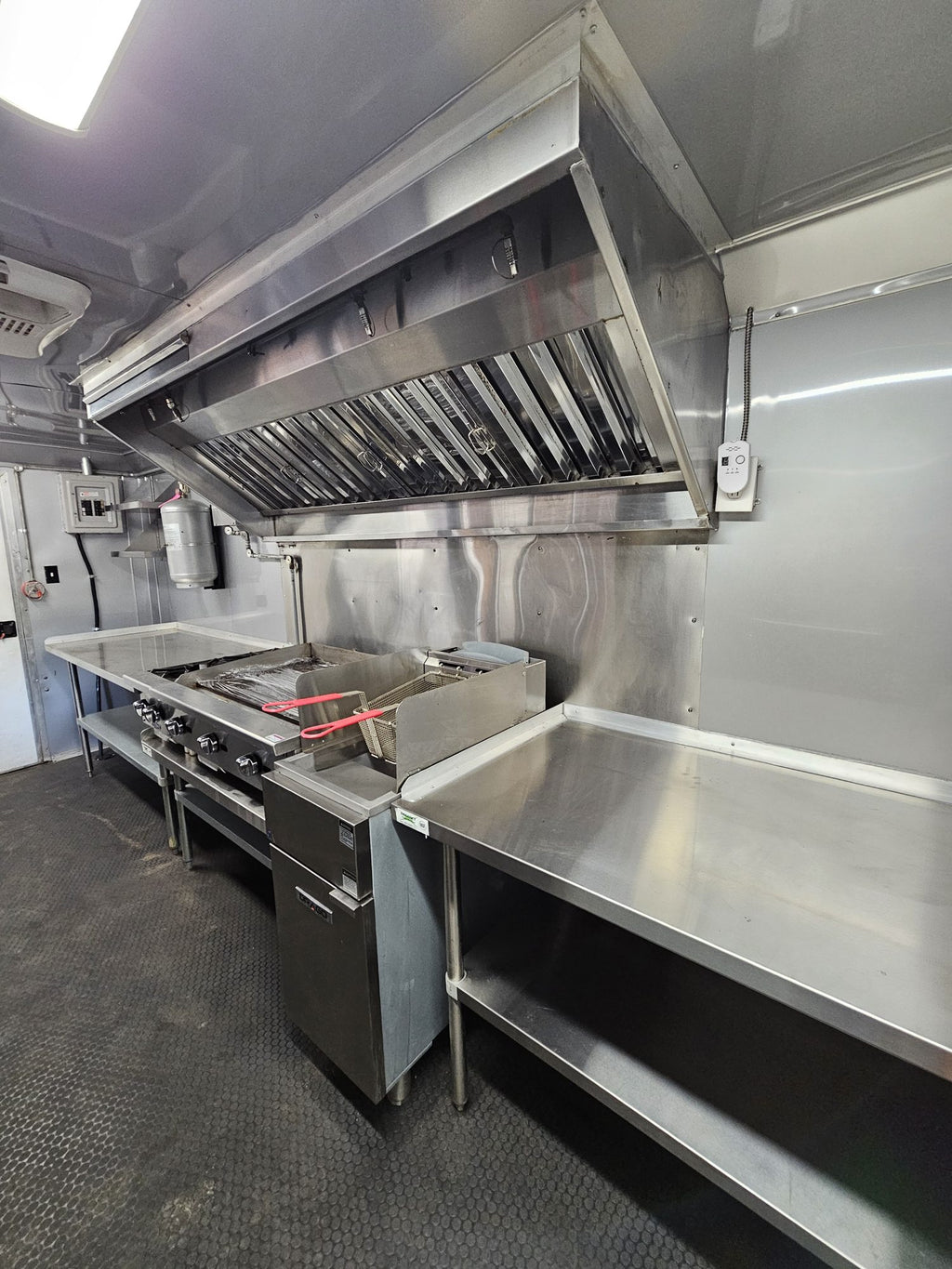 Cook line with griddle and fryer beneath the stainless vent hood