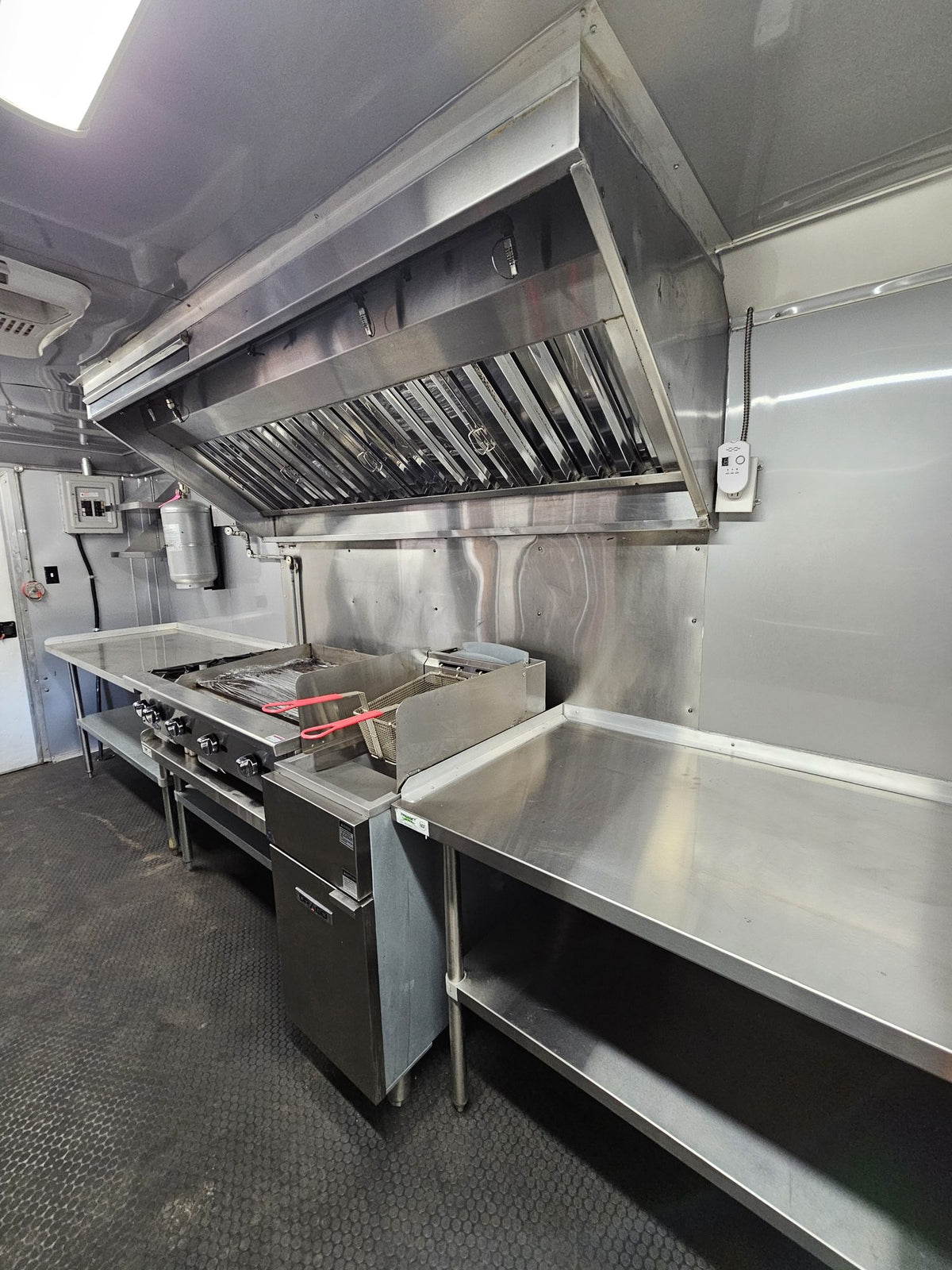 Cook line with griddle and fryer beneath the stainless vent hood